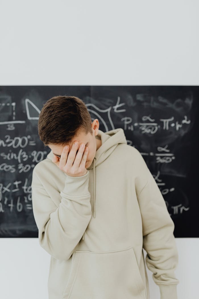 Resigned Young Man in front of Blackboard with Trigonometry Calculations